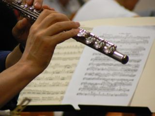 Close-up van hand met dwarsfluit, op de achtergrond bladmuziek